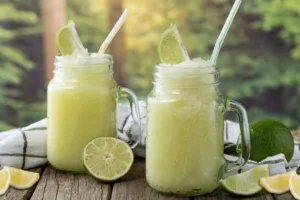 A frosty protein drink slushie served in a tall glass with a straw and fruit garnish.